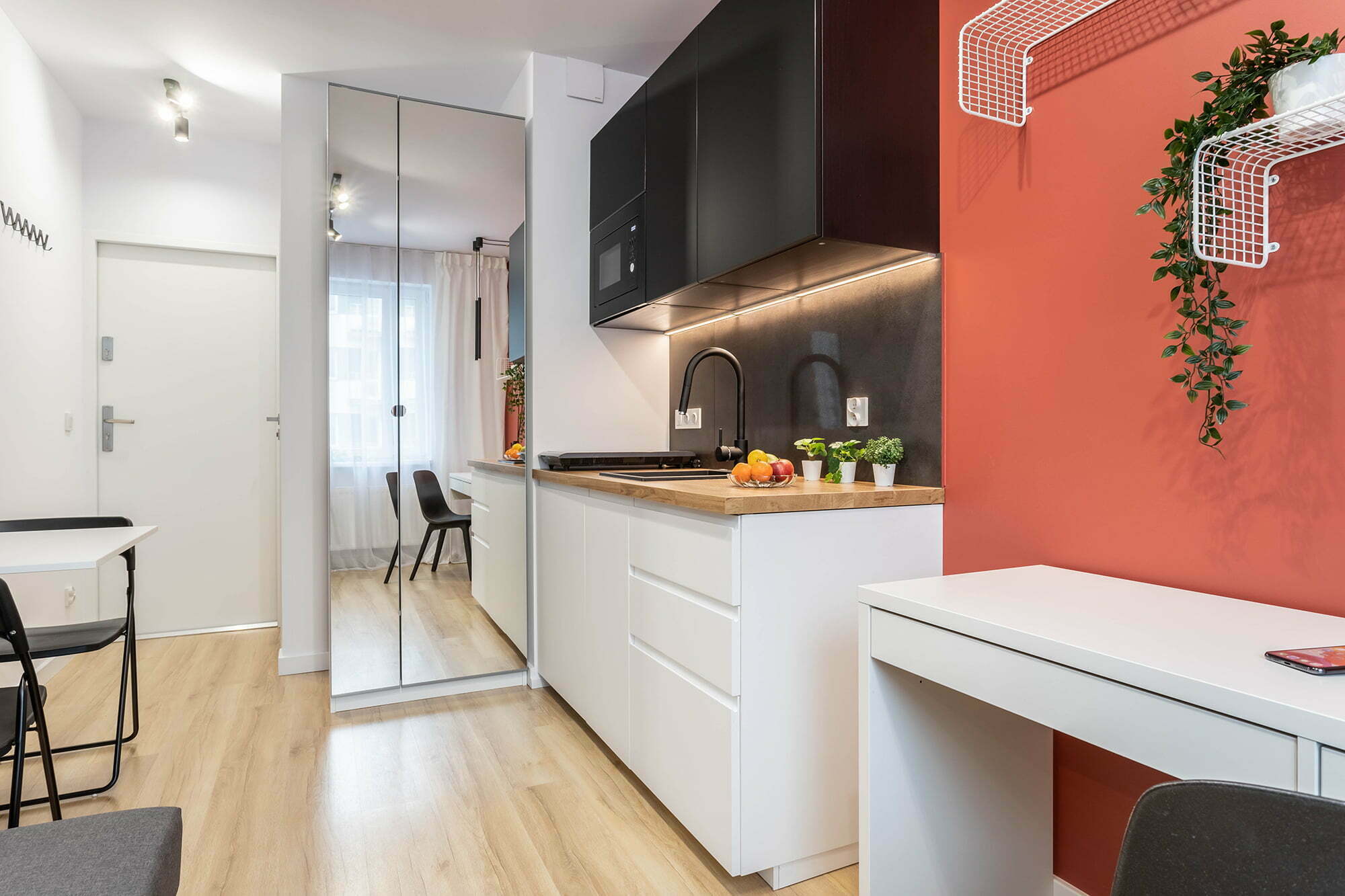 salon z aneksem kuchennym mała biało pomarańczowa minimalistyczna aranżacja Beata Kołodziejczyk
