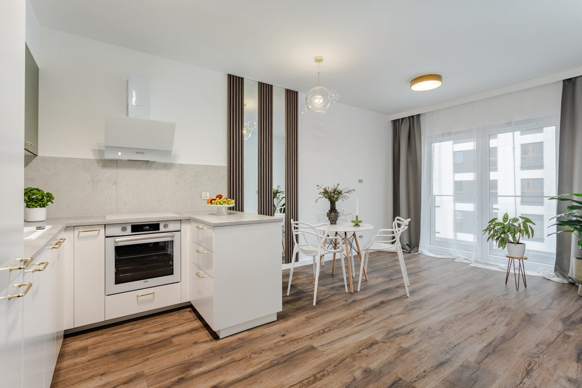 salon z aneksem kuchennym duży biały szałwia zielony ciemna podłoga lamele lustra złote dodatki minimalistyczny aranżacja Beata Kołodziejczyk